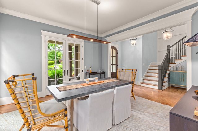a dining room with wooden floor a chandelier a glass table and chairs