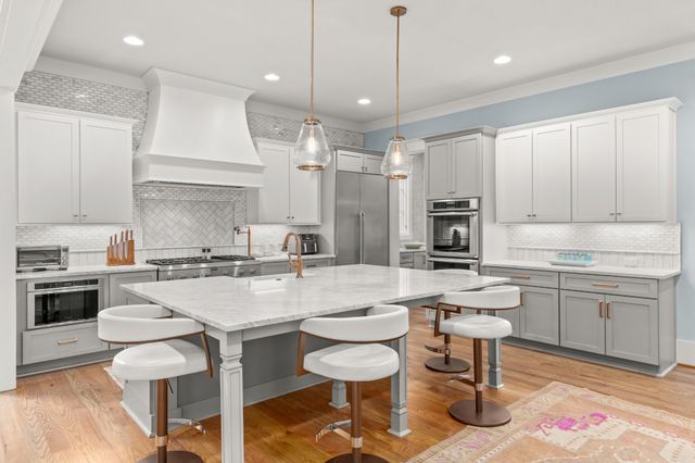 a kitchen with a dining table chairs stove and white cabinets