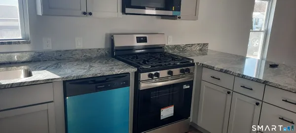 a kitchen with granite countertop a sink cabinets and stainless steel appliances