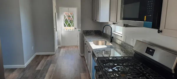 a kitchen with granite countertop a stove and a wooden floor