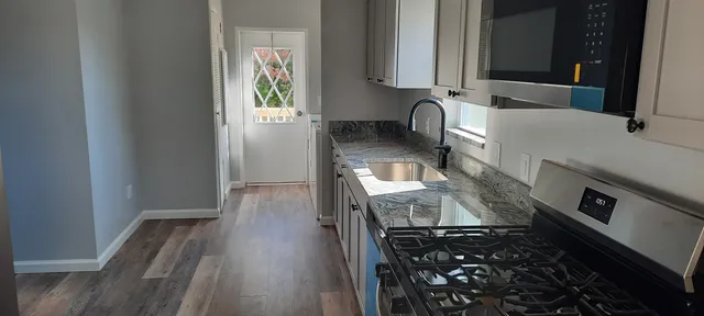 a kitchen with granite countertop a stove top oven microwave and cabinets