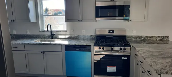 a kitchen with granite countertop a stove top oven microwave and cabinets