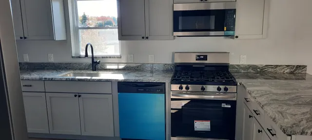 a kitchen with stainless steel appliances granite countertop a sink stove and microwave