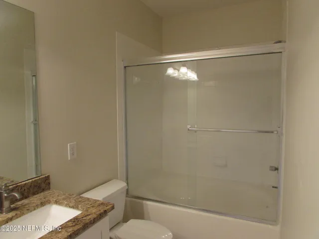 a bathroom with a granite countertop shower and a sink