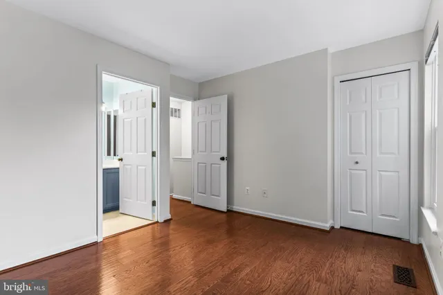 a view of an empty room with wooden floor and closet area