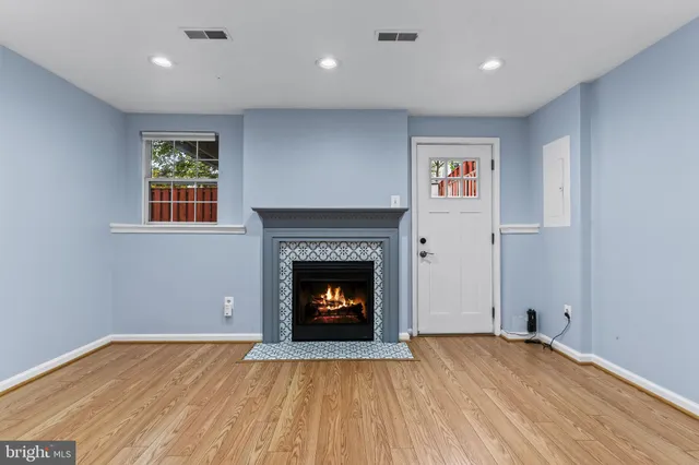 a view of an empty room with wooden floor fireplace and a window