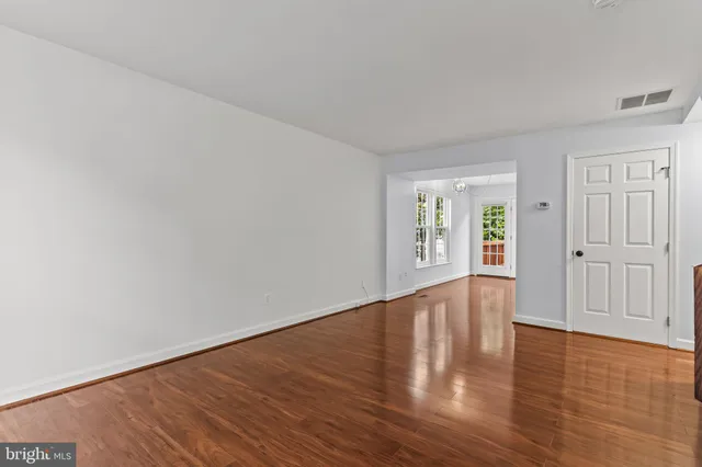 a view of an empty room with wooden floor and window