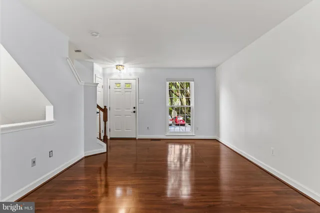 a view of hallway with window and wooden floor