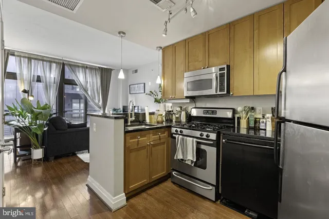 a kitchen with kitchen island granite countertop stainless steel appliances and wooden cabinets