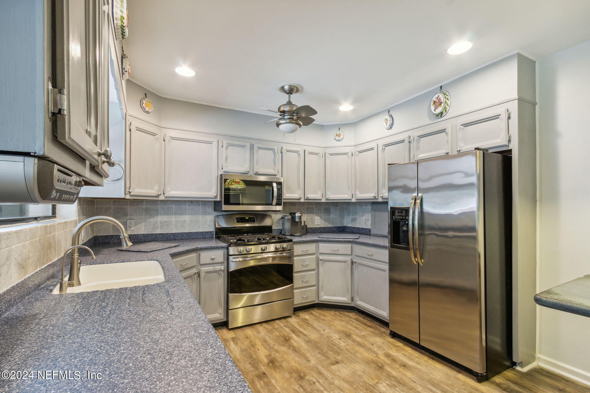 1605 Brookwood Road Jacksonville, FL 32207 - Photo 14 of 40 a kitchen with stainless steel appliances granite countertop a refrigerator a stove a sink and a microwave with wooden floor