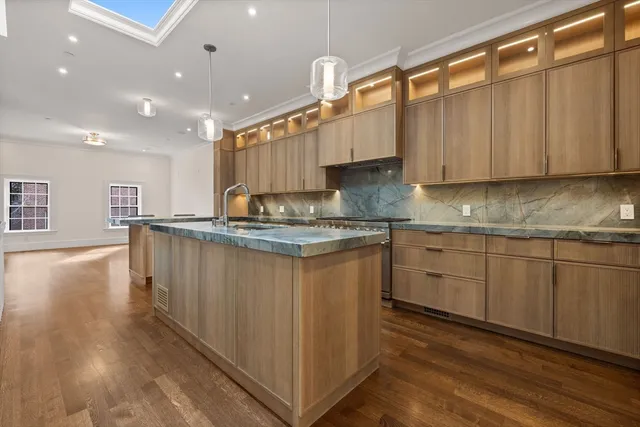 a kitchen with kitchen island granite countertop a sink cabinets and wooden floor
