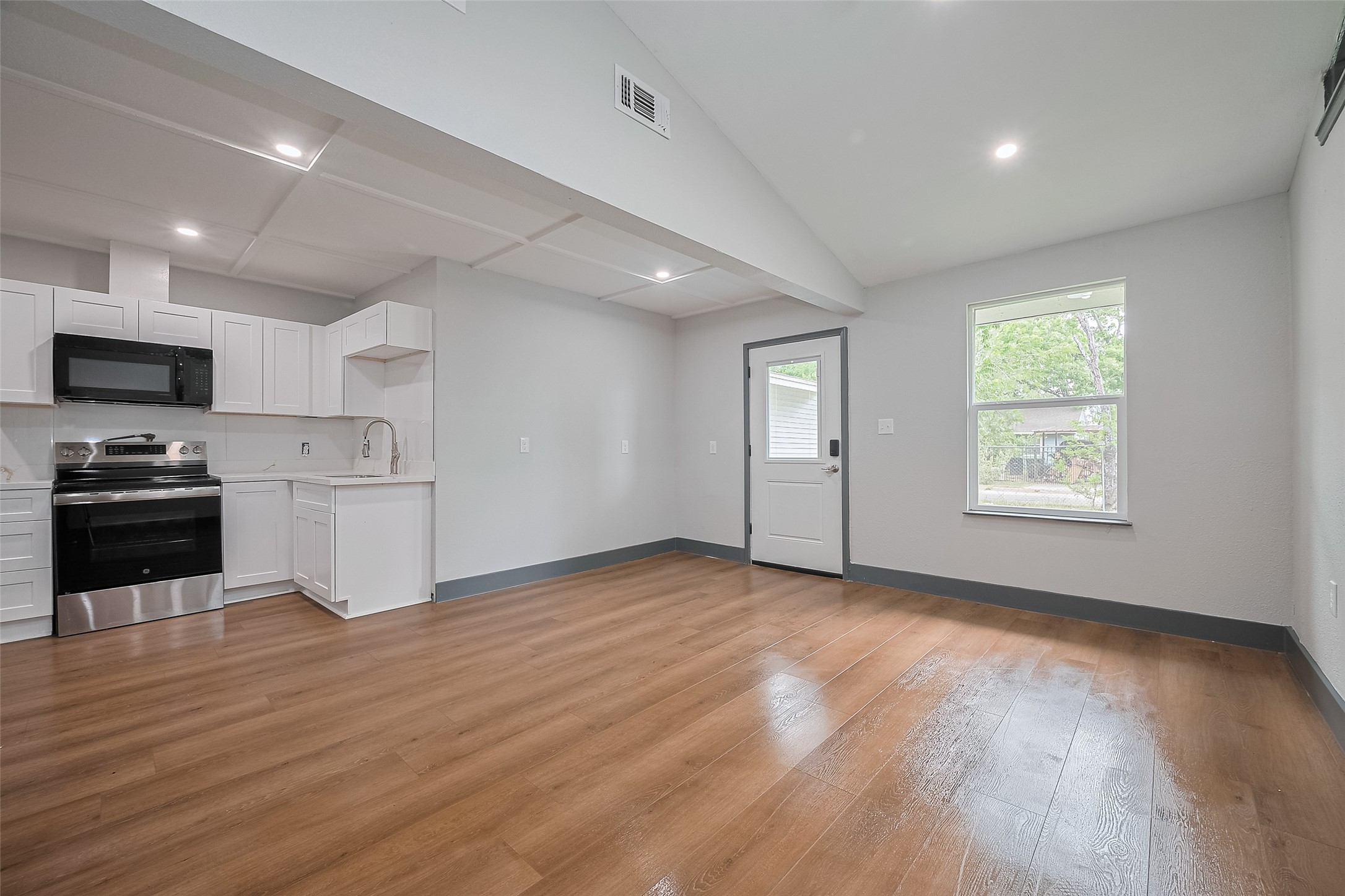 6058 Lyndhurst Drive Houston, TX 77033 - Photo 12 of 50 an empty room with wooden floor kitchen view and windows