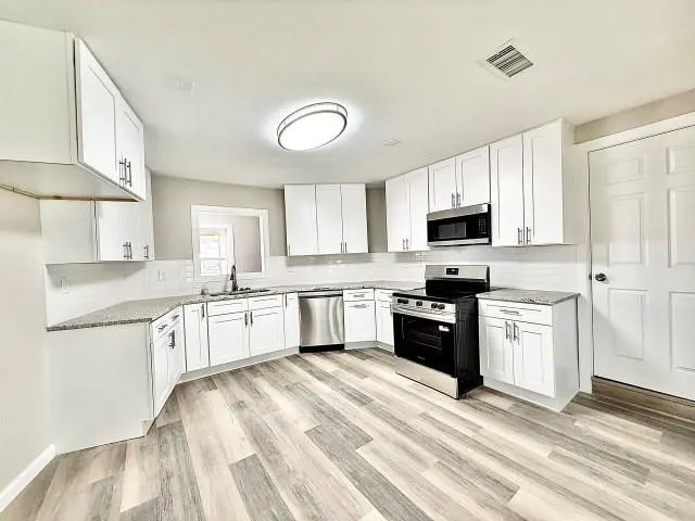 a kitchen with granite countertop a sink a counter top space stainless steel appliances and cabinets