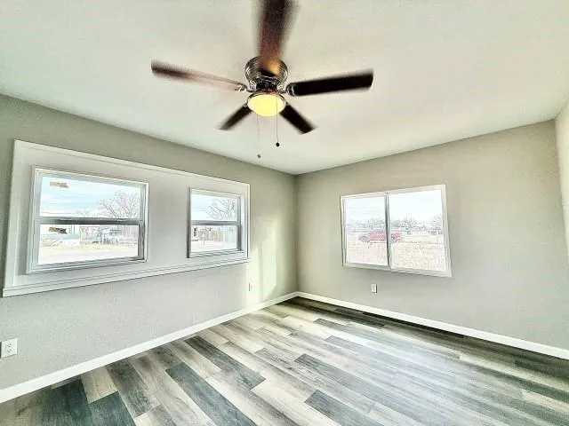 a view of empty room with wooden floor and fan