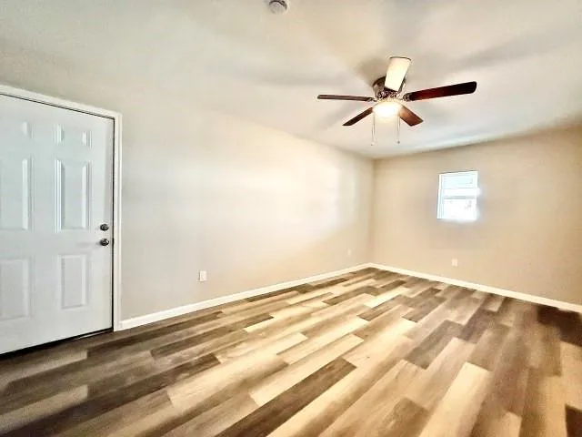 a view of empty room with wooden floor and fan