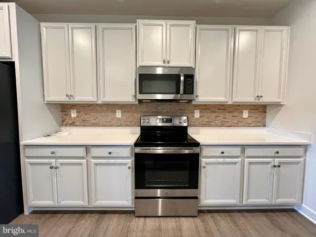 a kitchen with granite countertop white cabinets and stainless steel appliances