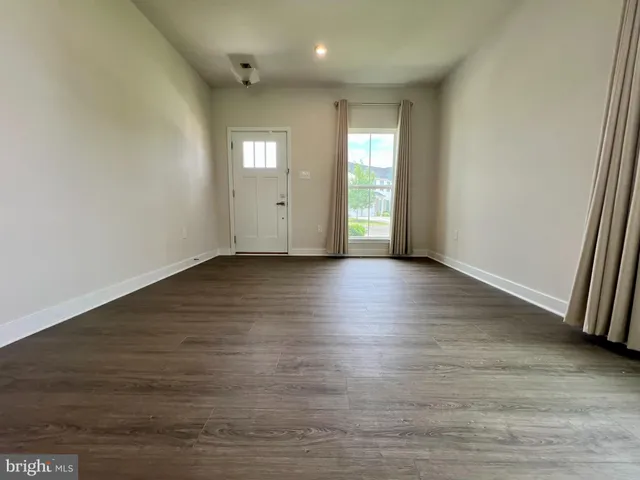 a view of an empty room with window and wooden floor