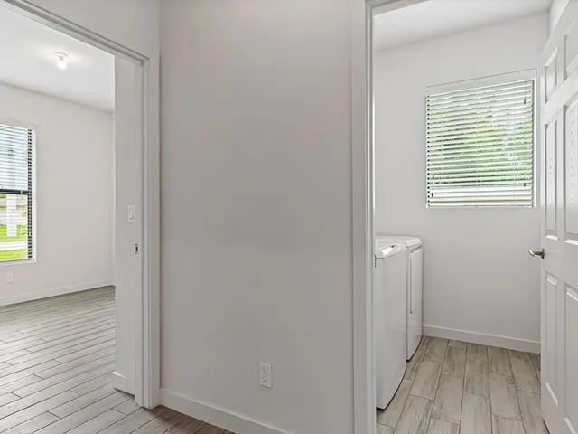 a view of hallway with window and wooden floor