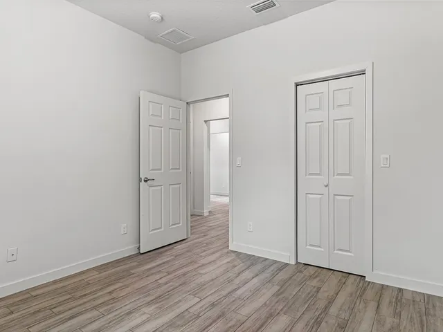 an empty room with wooden floor and closet area