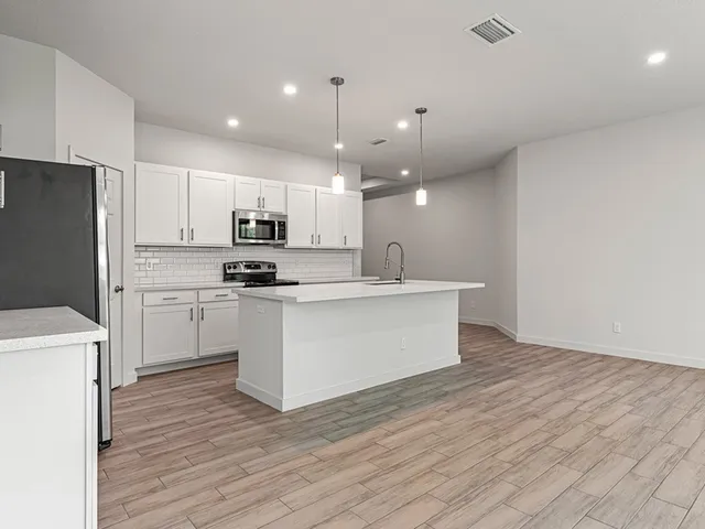 a view of kitchen with granite countertop cabinets and refrigerator