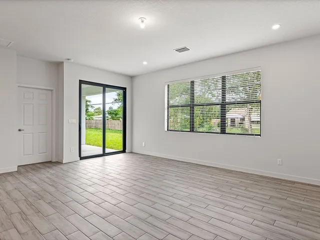 a view of an empty room with a window and wooden floor