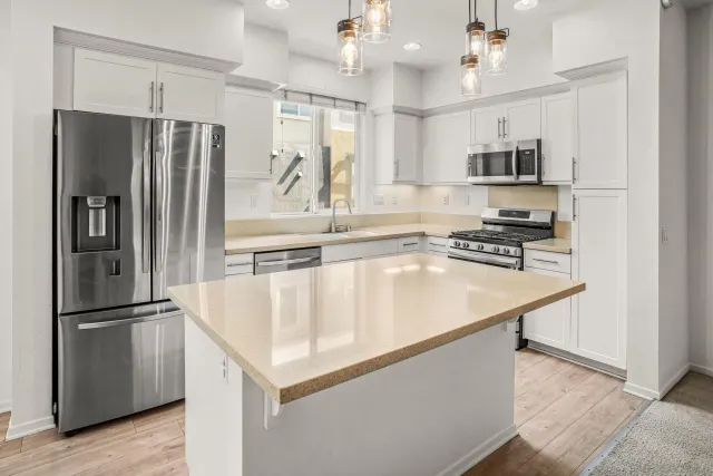 a kitchen with stainless steel appliances granite countertop a refrigerator a sink and a stove