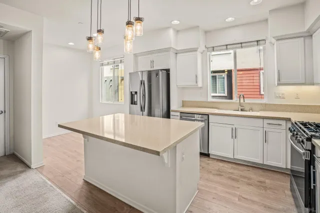 a kitchen that has a lot of white cabinets and stainless steel appliances