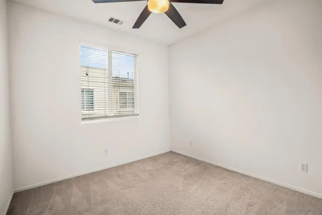 an empty room with a window and a ceiling fan