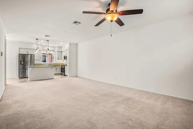 an empty room with a kitchen and a ceiling fan