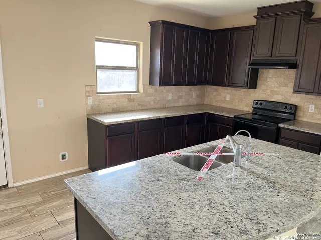 an empty room with a window and a chandelier fan