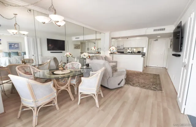 a dining room with wooden floor a chandelier a glass table and chairs