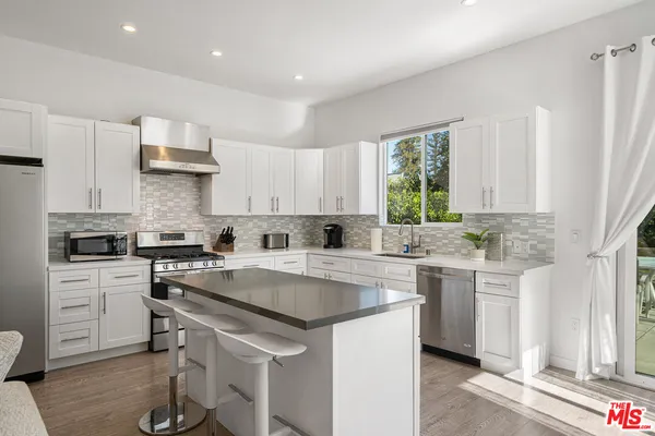 a kitchen with a sink a stove a refrigerator and white cabinets