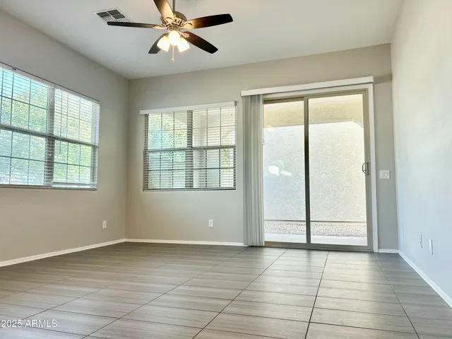 a view of an empty room with window and chandelier fan