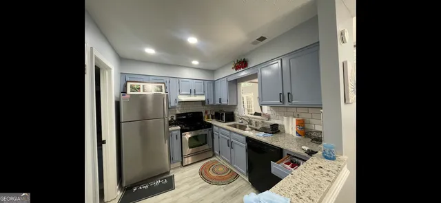 a kitchen with stainless steel appliances granite countertop a refrigerator a stove and a sink