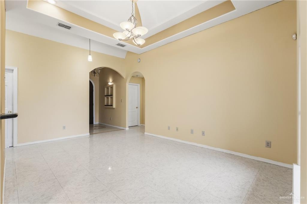 1720 East 2nd Street Weslaco, TX 78596 - Photo 5 of 17 an empty room with a chandelier fan and windows