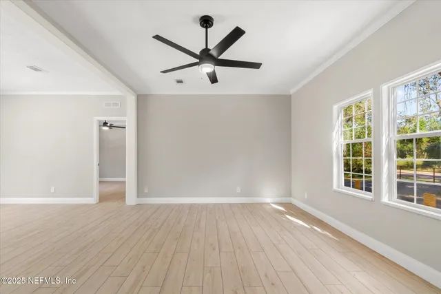 an empty room with wooden floor and windows