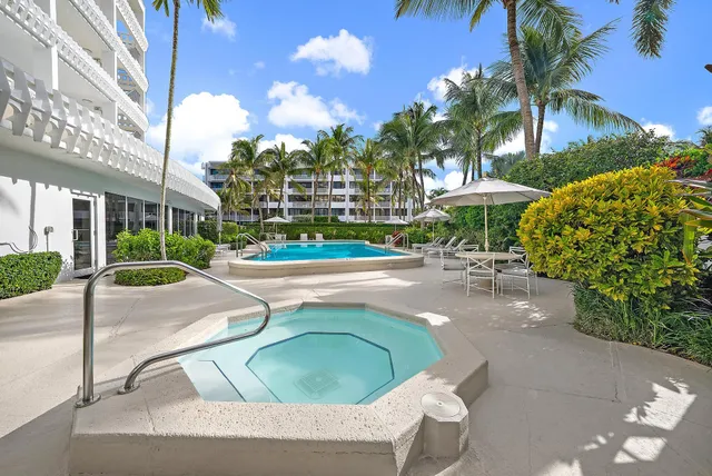 a view of a swimming pool with lawn chairs under an umbrella