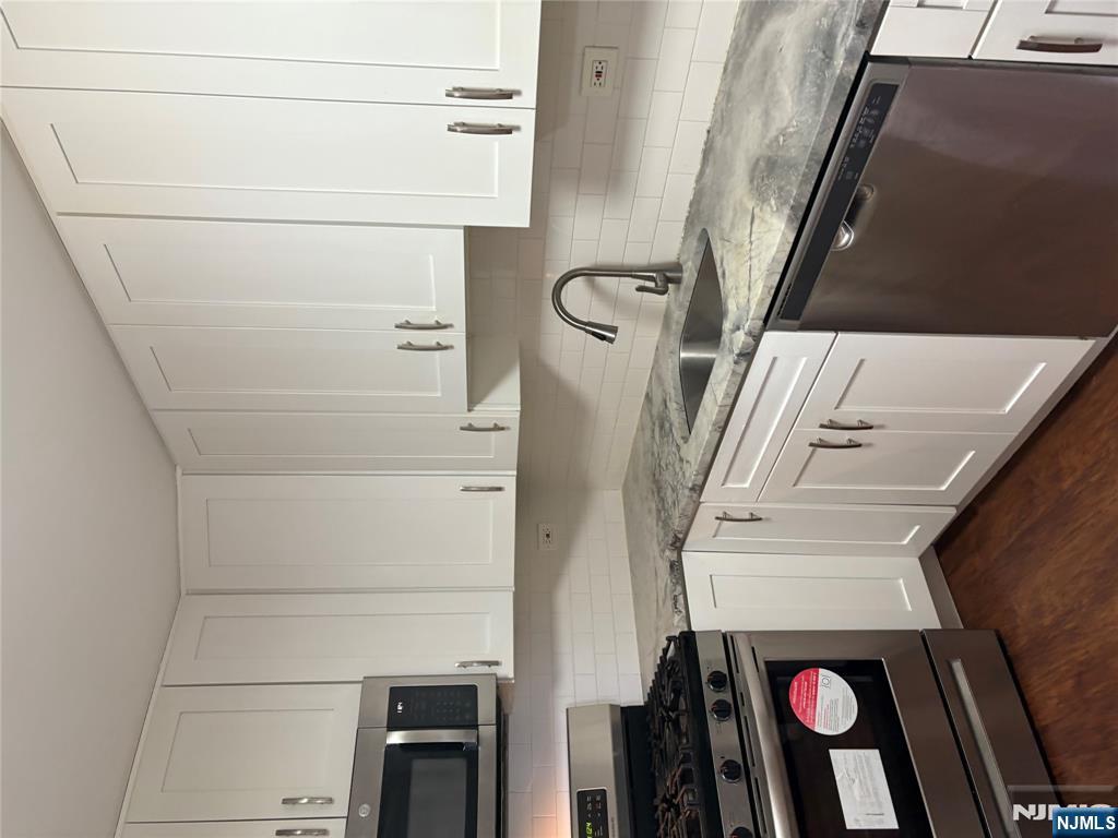 39 East 39th Street, Unit 412 Paterson, NJ 07514 - Photo 11 of 21 a kitchen with granite countertop white cabinets and stainless steel appliances