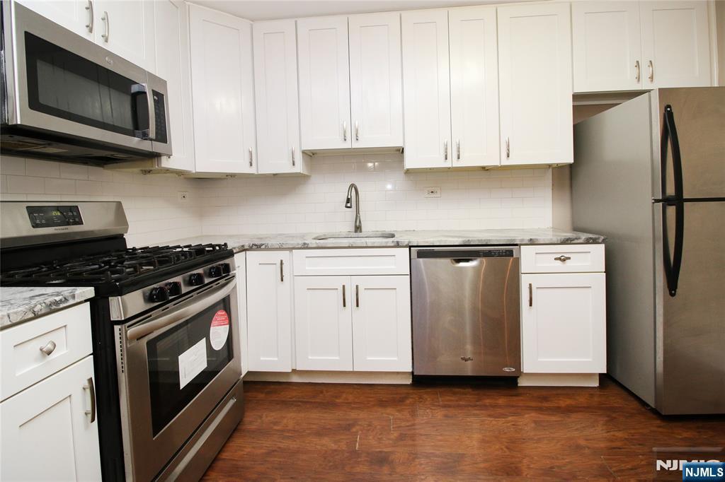 39 East 39th Street, Unit 412 Paterson, NJ 07514 - Photo 17 of 21 a kitchen with stainless steel appliances granite countertop a stove top oven microwave and refrigerator