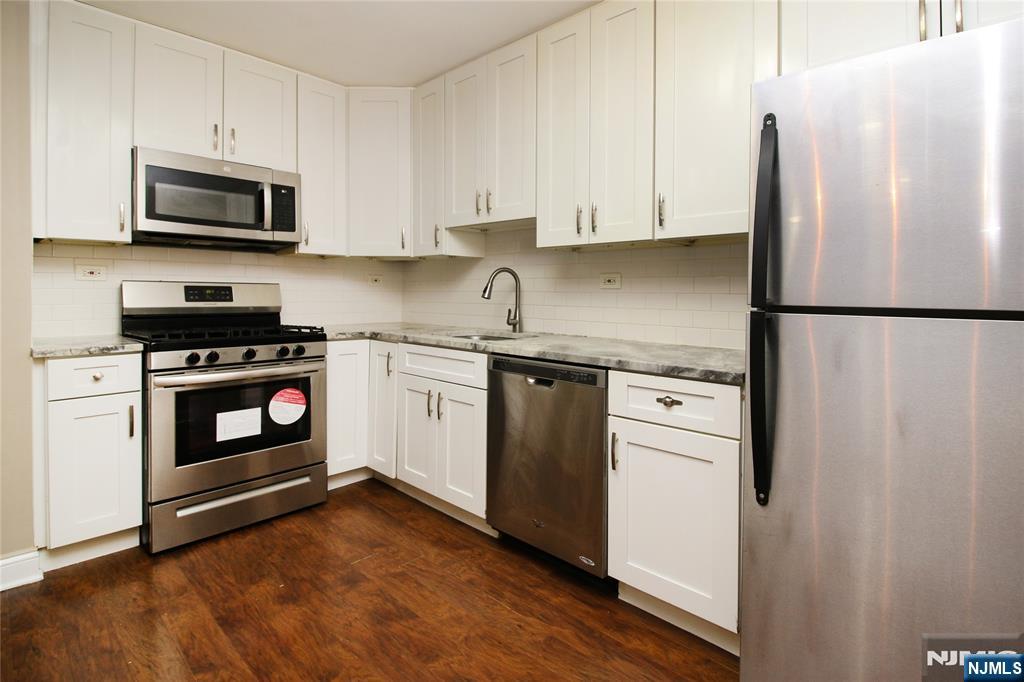 39 East 39th Street, Unit 412 Paterson, NJ 07514 - Photo 18 of 21 a kitchen with white cabinets and stainless steel appliances