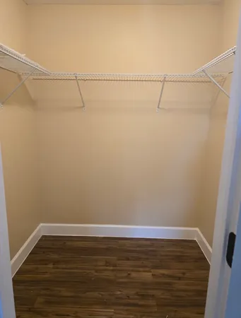 an empty room with wooden floor ceiling fan and windows