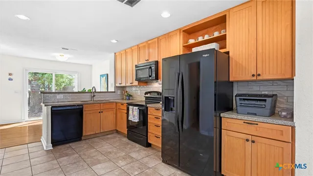 a kitchen with stainless steel appliances granite countertop a refrigerator a stove top oven and sink