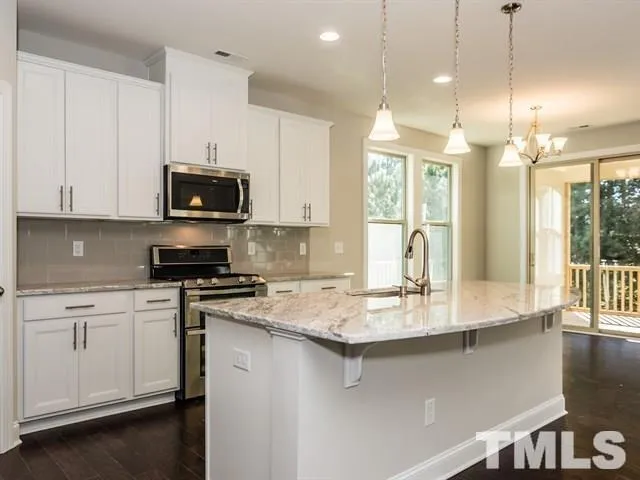 a kitchen with stainless steel appliances granite countertop a sink a stove and a microwave