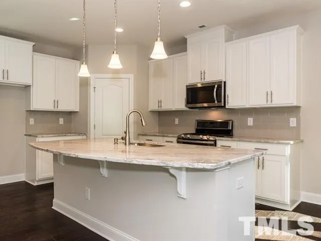 a kitchen with stainless steel appliances granite countertop a sink a stove a microwave a counter top and cabinets