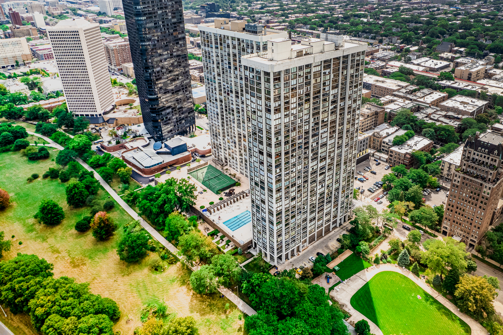 an aerial view of multi story residential apartment building with yard and large trees