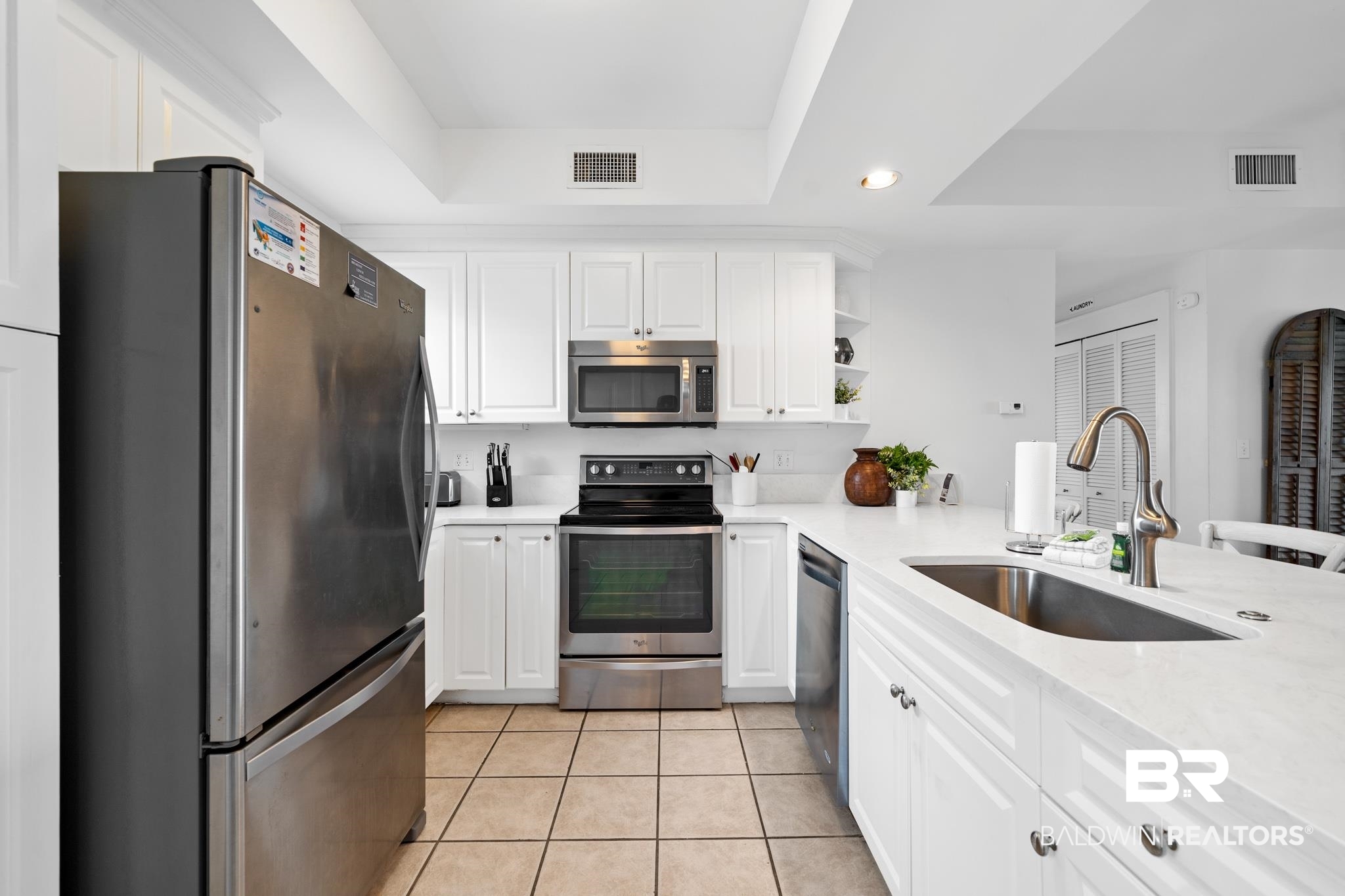815 Plantation Road, Unit 301 Gulf Shores, AL 36542 - Photo 3 of 29 Kitchen with light countertops, a raised ceiling, a sink, visible vents, and appliances with stainless steel finishes
