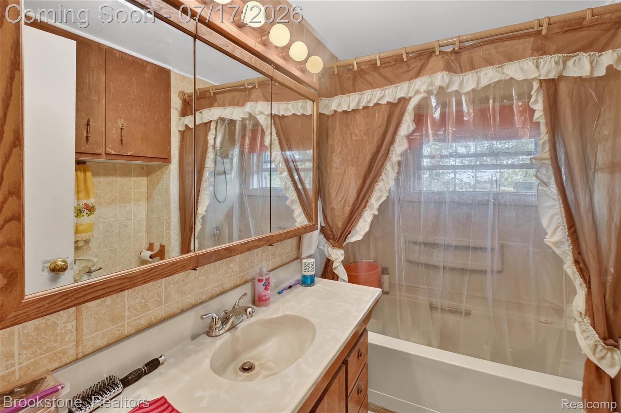 22025 Lakefield Road Merrill, MI 48637 - Photo 28 of 47 Bathroom featuring a vanity with an integrated sink, a large mirror with a built-in medicine cabinet, above-mirror lighting, wood-finish cabinetry, and tiled walls