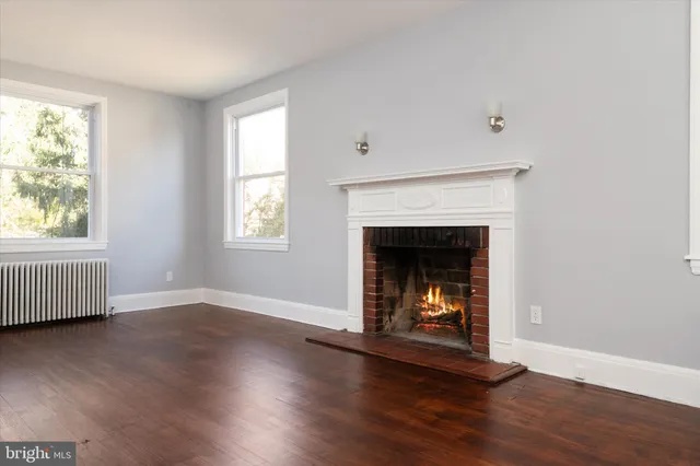 an empty room with wooden floor fireplace and windows