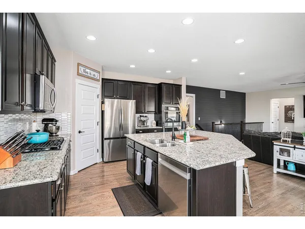 a kitchen with stainless steel appliances granite countertop a table chairs stove and refrigerator