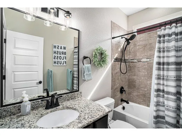 a bathroom with a granite countertop sink a mirror and shower